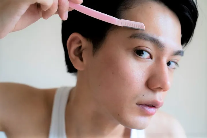 カミソリで眉を整える男性